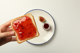 Fototapeta Tulipany - Fig jam, plate and toaster bread in hand on white background, top view