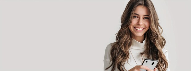 Wall Mural - Photo of An elegant woman in her 20s with long wavey hair, smiling while using smartphone on a white background with copy space for text or product. Web banner. Mobile phone use