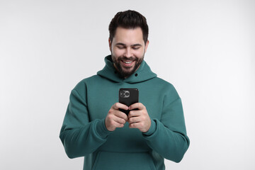 Wall Mural - Happy young man using smartphone on white background