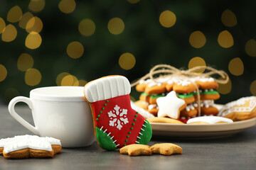 Wall Mural - Decorated cookies and hot drink on grey table against blurred Christmas lights