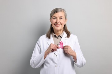 Wall Mural - Mammologist with pink ribbon on gray background. Breast cancer awareness