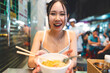 Asian foodie tourist woman eating wonton noodles at China town asia street food night market