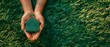 Hands holding a green house model over a grassy surface
