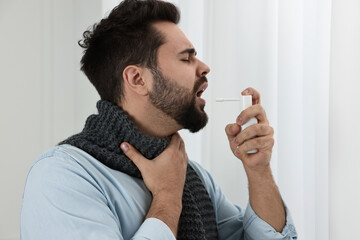 Sticker - Young man with scarf using throat spray indoors