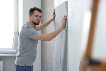 Poster - Man hanging stylish gray wallpaper in room