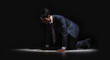 失敗し暗い部屋で跪き項垂れ絶望するスーツを着た仕事中のビジネスマンの日本人男性　後悔・謝罪・増税・落ち込む・鬱・破産のイメージ