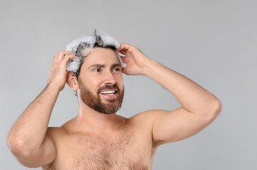 Sticker - Happy man washing his hair with shampoo on grey background