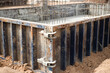 Reinforced concrete foundations support a bustling construction site filled with a variety of pipes as workers install essential infrastructure