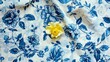 A blue and white floral patterned tablecloth with a single yellow rosebud resting in the center. 