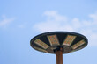 Selective focus solar cell lamp in the shape of a UFO on a tall pole against a bright sky background. There is space for text.