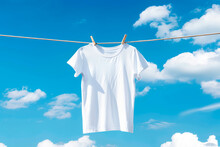 White T-shirt Hanging On Clothesline Against Blue Sky With Clouds