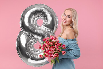 Wall Mural - Happy Women's Day. Charming lady holding bouquet of beautiful flowers and balloon in shape of number 8 on pink background
