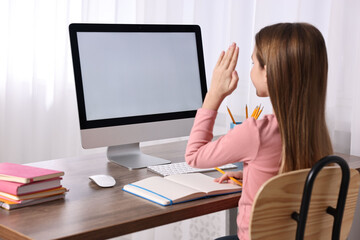 Sticker - E-learning. Girl raising her hand to answer during online lesson at table indoors