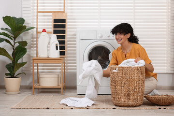 Canvas Print - Happy woman with laundry near washing machine indoors