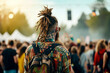 A stylish man with dreadlocks is viewing a stage at an outdoor festival, capturing the essence of youth and music culture