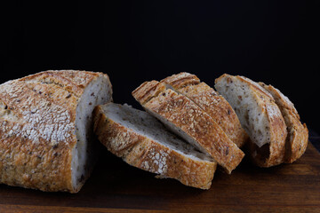 Cut loaf with seeds on a wooden board. Sliced pieces of bread. Art bread.