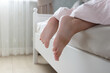 Feet under a light blanket on the bed, soft focus background