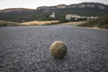 closeup of isolated tennis ball sitting on an empty road, black and white