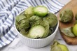 Fresh green tomatillos with husk in bowl on light table, closeup