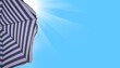 Travel, summer holiday and vacation concept. Beach umbrella on blue summer sky background
