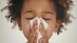 Young child with curly hair eyes closed using a white tissue to wipe their nose conveying a sense of comfort and care.