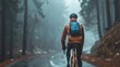 A cyclist in an orange jacket and blue backpack riding down a misty forested road.