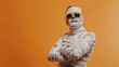 ©  Mohammad Xte - Young man in costume dressed as a Halloween cosplay of a scary mummy on orange background