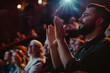 Man with beard in a audience in a theater applauding clapping hands
