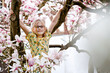 Cute spring fashion preschool girl with glasses under blossom magnolia tree. Little happy child and spring.