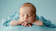 Cute studio photography of a newborn baby boy sleeping with cute props on soft blue background