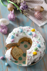 Wall Mural - Glazed easter lemon cake decorated with confectionery and mini chocolate eggs candy on a wooden table.