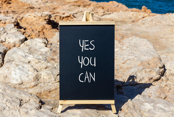 Wall Mural - Motivational and Yes you can symbol. Concept words Yes you can on beautiful black chalk blackboard. Beautiful red stone blue background. Business motivational and Yes you can concept. Copy space.