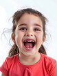 © Nikka - Exuberant Little Girl with Dark Hair Laughing Heartily in Coral Red Top Against a Light Background with Copy Space