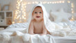 Cute portrait of a happy baby wrapped with a white towel in bed after a bath. Concepts of parenting, hygiene, care and growth.