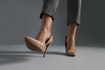 Businesswoman in beige shoes on grey background, closeup