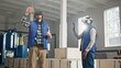 Close up of two male middle-aged engineers in headset and blue vests standing in factory and having wonderful virtual reality experience. Indoors. Men in VR goggles moving their hands in air.