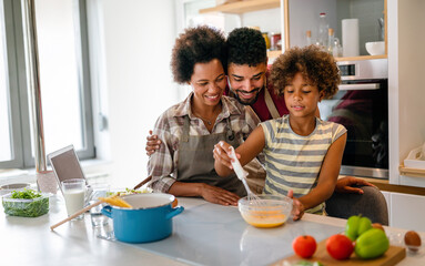 Wall Mural - happy african american parents and child having fun preparing healthy food in kitchen