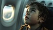 A young boy appears tearful and anxious as he gazes out of an airplane window during sunset, possibly experiencing aerophobia.
