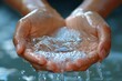 Close-up shot of clear water held in cupped hands with droplets falling back down
