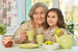 Old woman with a young girl drinking tea on the table
