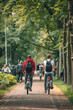Two people enjoying a leisurely bike ride along a picturesque city pathway with  both wearing large black backpacks
