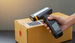 Close-up electronic portable barcode reader reads the barcode from the cardboard box, copy space.