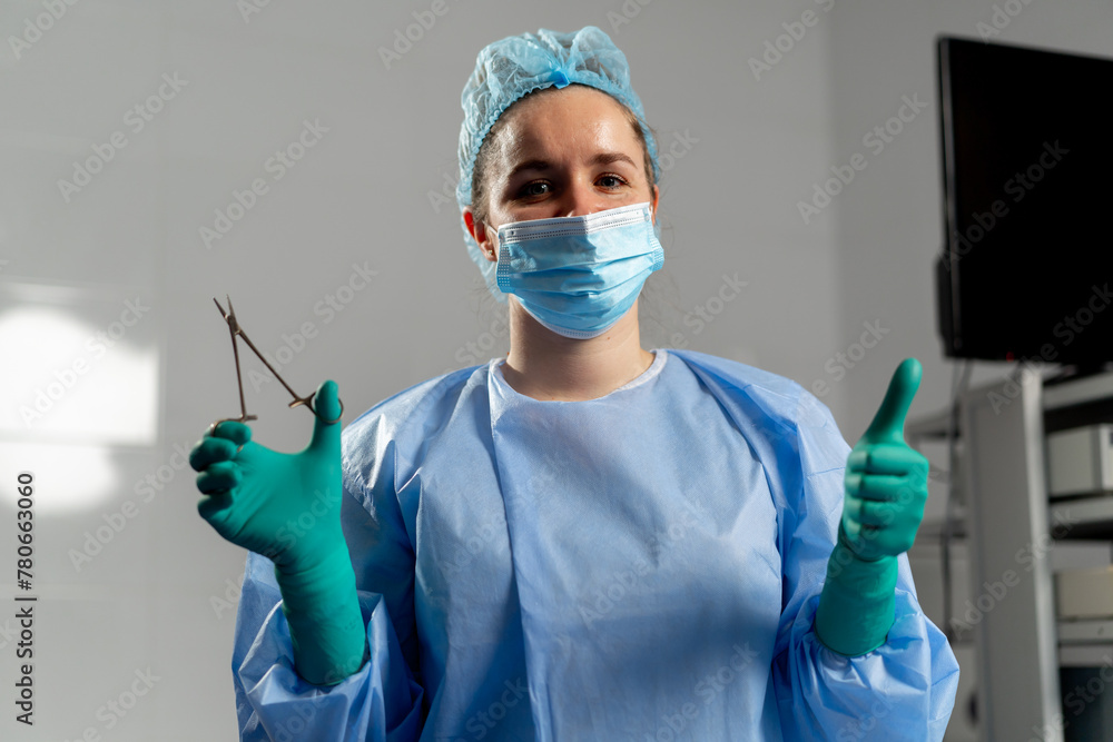 female surgeon in a mask in the operating room stands with a sterilized ...