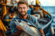 happy man fisherman holds big sea tuna fish in hands on boat in ocean in summer
