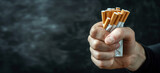 Fototapeta  - Close up man's hand squeezing a pack of cigarettes, concept of the harm of smoking to health and quitting smoking