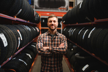 Wall Mural - Glad male customer taking new tires in the supermarket for buying. He looks happy. Big shopping mall with car goods