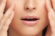 Lips and fingers on face of young beautiful woman close-up