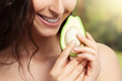 Avocado in hands of young woman in nature close-up