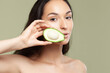 Young beautiful woman holding avocado half on pistachio background