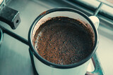 Fototapeta Tęcza - Fresh natural brewed coffee on the gas stove top. in an iron mug